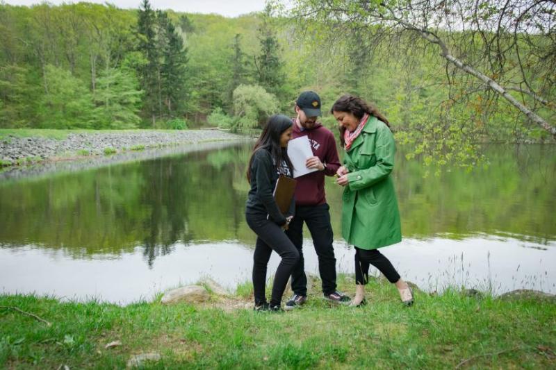 Three students conducting research outdoors near a lake