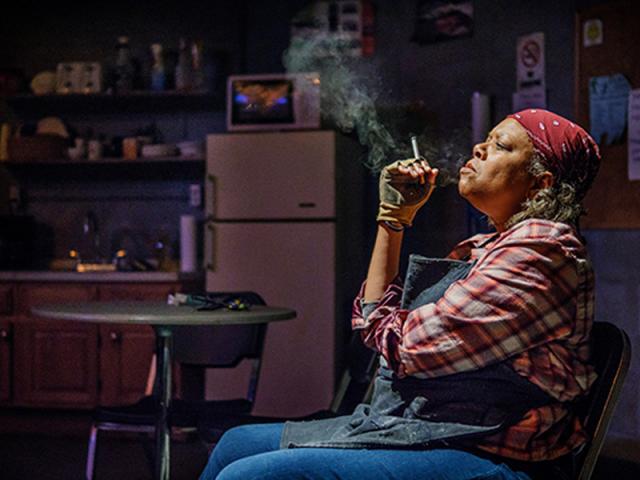 A woman smokes a cigarette in a dark room