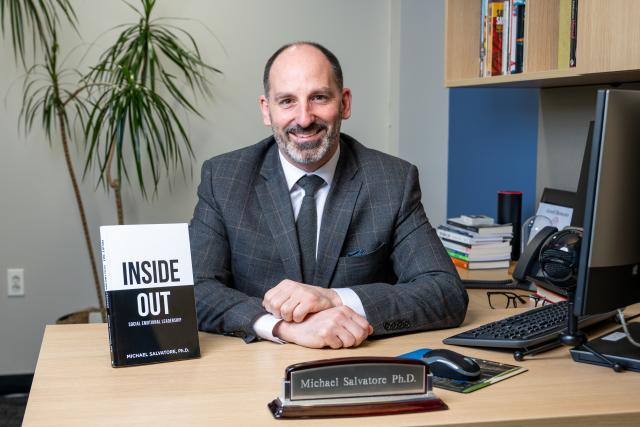 Mike Salvatore in a posed shot at his desk, showing his new book, Inside Out