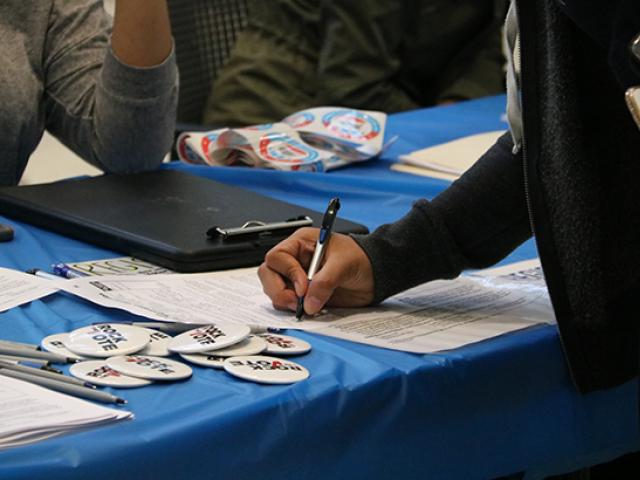 A closeup of a student registering to vote at a desk.