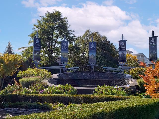 The fountain on Kean's campus, with flags displaying names of the Kean campuses