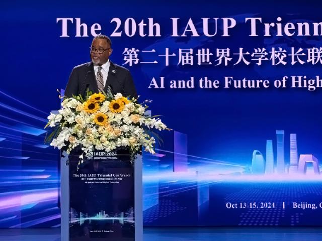 Kean University President Lamont O. Repollet, Ed.D. speaks at a podium festooned with flowers at the 20th IAUP Conference in China