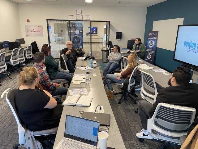 Bruce Waltuck, seated at a long table, leads a group of attendees in a social enterprise workshop at Kean.