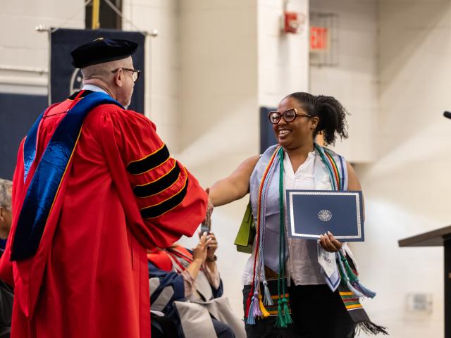Graduating student shakes hands with Provost David Birdsell