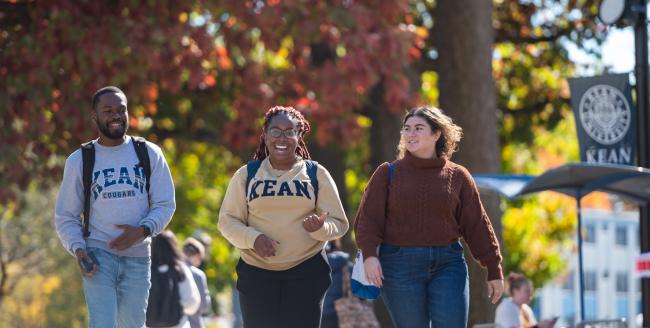 Kean students walk against a fall foliage backdrop 