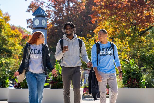 Kean students walk against a backdrop of fall scenery. 