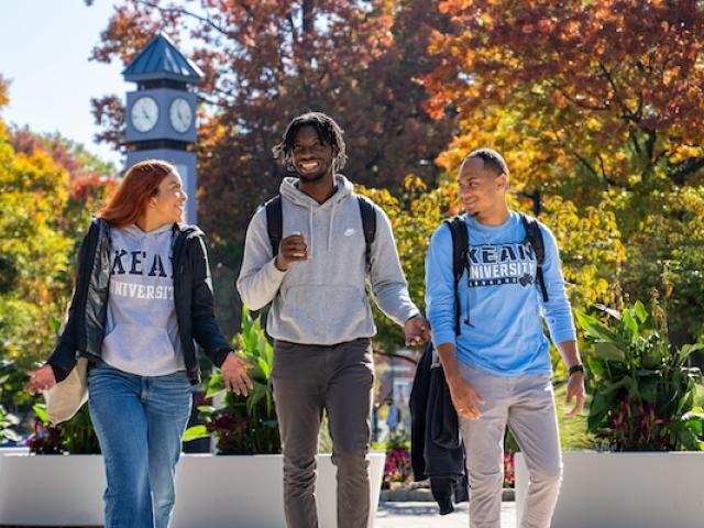 Kean students walk down Cougar Walk against a backdrop of Fall foliage 