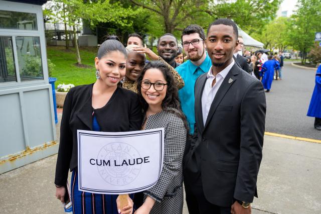 Cum Laude students pose behind their sign saying they are cum laude