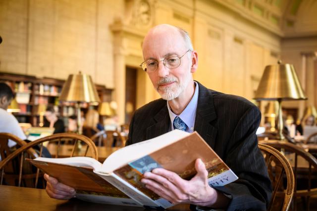 Dr. Jeff Toney sits reading a book at the MIT library