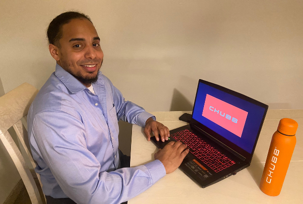 Kean math graduate Angel Rivera sits at a laptop with a Chubb water bottle nearby.