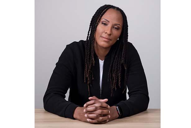 Chamique Holdsclaw, sitting, with her hands folded on a desk.