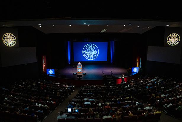 An overhead shot of Wilkins Theatre with President Repollet at the podium and the audience in their seats.