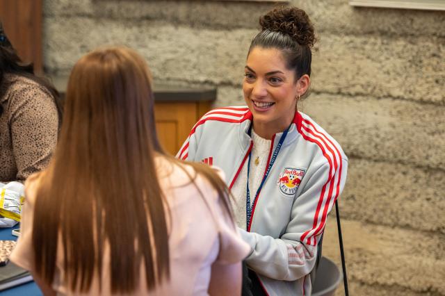 Woman in Red Bulls sweatshirt talks to a student