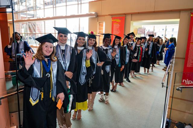 Graduates in robes lined up in the hallway before Commencement