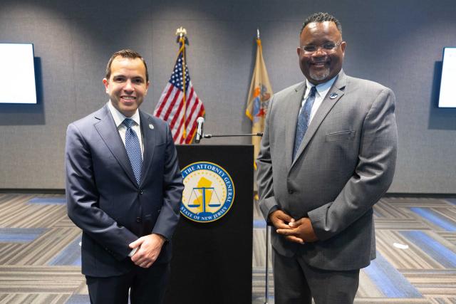 The attorney general and the Kean president stand at a podium