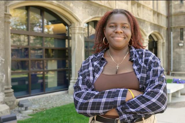 Oluwatunmise Alabi stands outside Kean Hall, grinning with her arms crossed.