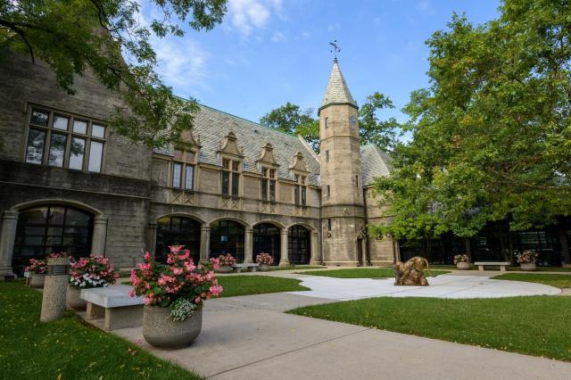 Kean Hall, with flowering plants and the Kean cougar statue