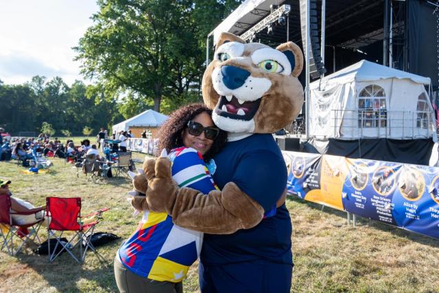 Keanu the Cougar, the Kean mascot, hugs a festival-goer.