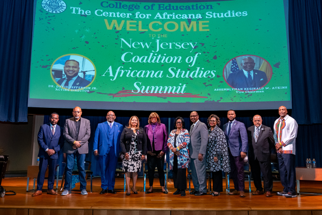 The speakers and panelists at the NJ Coalition of Africana Studies Summit pose on stage.