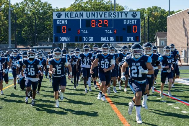 A group of boys wearing blue jerseys running on a football field