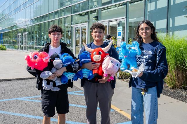 Two male and one female holding colorful stuffed animals