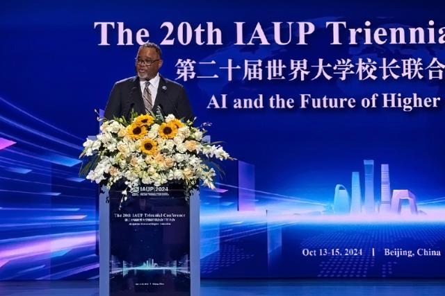 Kean University President Lamont O. Repollet, Ed.D. speaks at a podium festooned with flowers at the 20th IAUP Conference in China