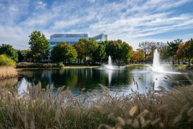 A pond with a fountain on Kean's campus. In the distance, is Kean's STEM Building