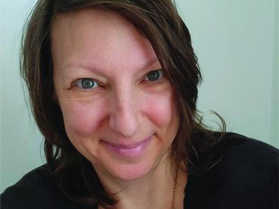  Jacquelyn Tuerk-Stonberg, Ph.D. wearing black shirt, necklace and smiling for headshot photo.