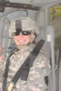 Sheila Farrell headshot in military vehicle wearing black shades and military uniform.